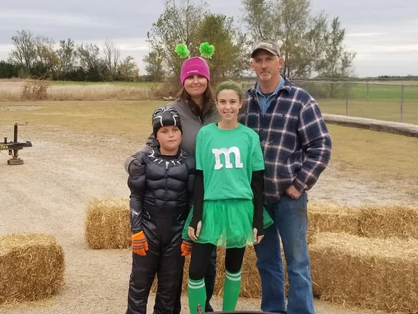 Four people in costumes standing outdoors beside hay bales in the church’s 2018 photo album.